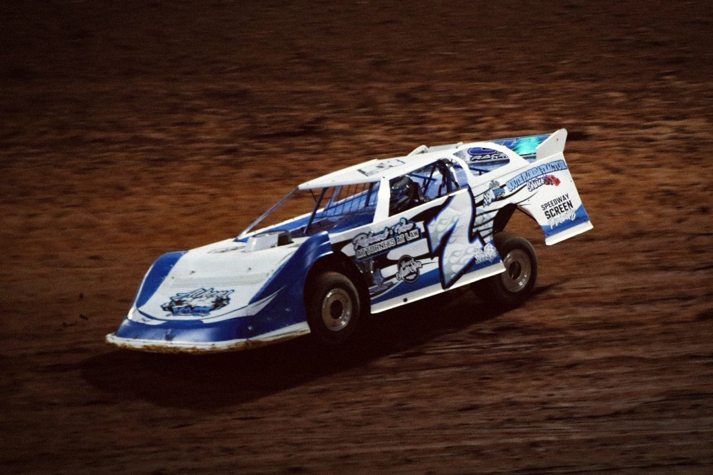 A dirt late model sliding through the turn at night